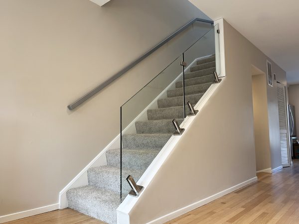 Stringer-mounted glass railing with stainless steel brackets