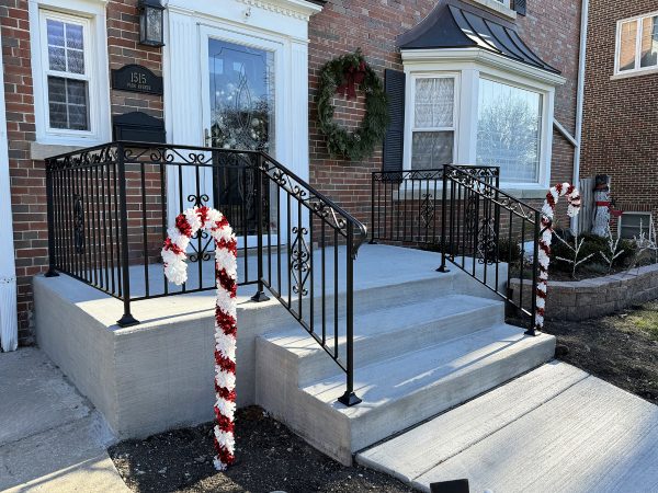Elegant iron entryway railing featuring detailed scroll designs and sturdy square posts.
