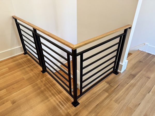 Interior geometric railing with horizontal bars and wood cap